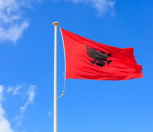 Top 10 Interesting Facts About Albania Albania flag. Albanian flag on a pole waving on blue sky background