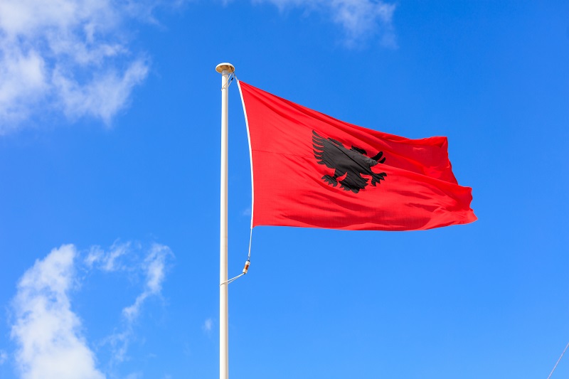 Albania flag. Albanian flag on a pole waving on blue sky background