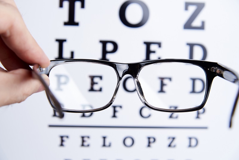 Glasses for vision in hands on the background of an eye chart