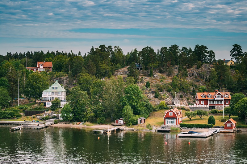 Sweden. Beautiful Red Swedish Wooden Log Cabin House On Rocky Is